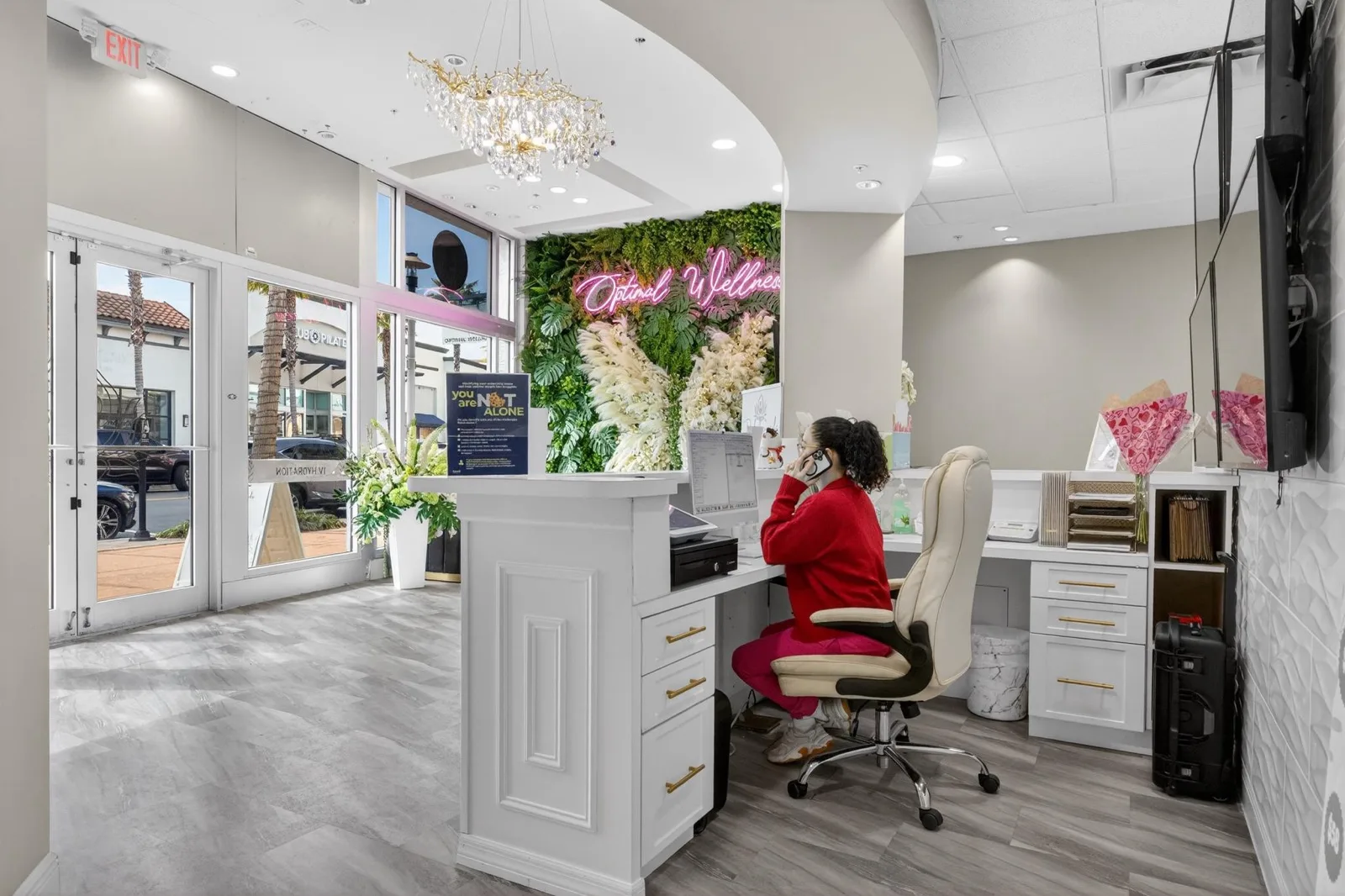 A team member working at the reception desk in front of the living wall and pink neon script