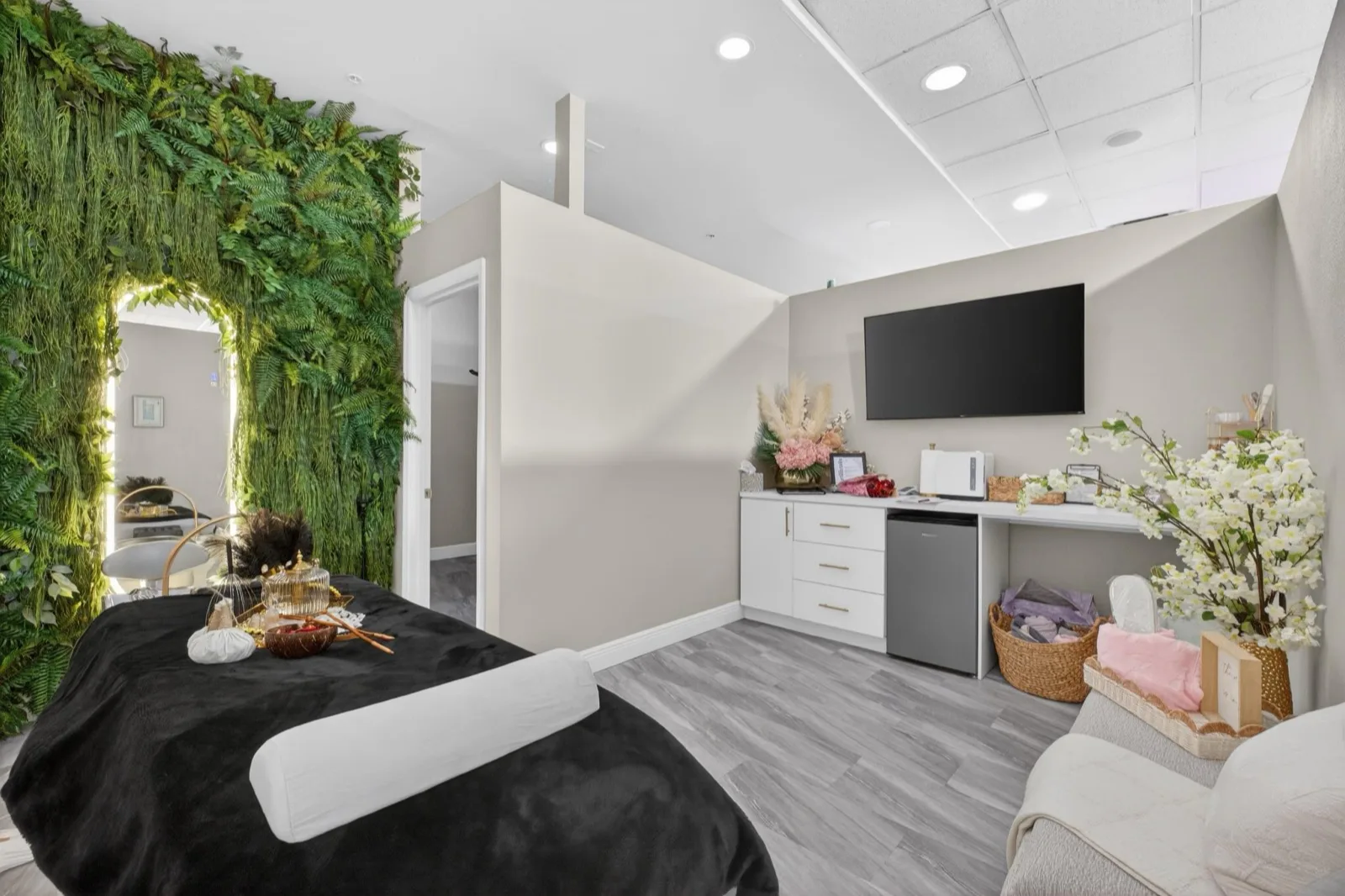 A head-spa suite with a wall screen, white cabinets and a bed dressed in white beside the living wall
